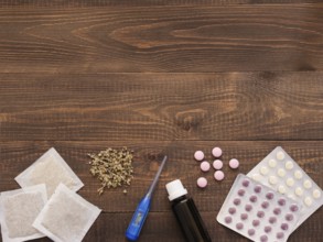Tablets, drops, herbals and thermometer on a dark wooden background with copy space. Herbal