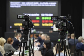 Camera during shareholders' meeting with big screen in the background