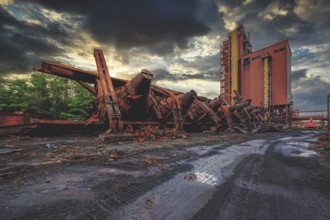 Dilapidated agricultural facility with a silo at sunset under dark clouds, HF6, Lost Place,