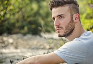 Portrait of handsome young man in white t-shirt outdoors, looking to a side