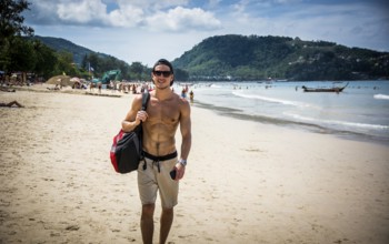 Half body shot of a handsome young man standing on a beach in Phuket Island, Thailand, shirtless