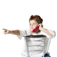 Very beautiful seven year old boy in a carnival wreath of brilliant red leaves. He sits astride a