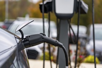 An electric vehicle recharges at a station while its owner is at work, allowing for a fully charged