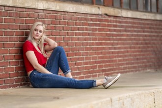 A beautiful blonde woman poses joyfully for the camera, showcasing her stylish spring clothing.