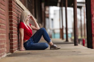 A beautiful blonde woman poses joyfully for the camera, showcasing her stylish spring clothing.