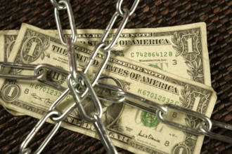 One Dollar notes in chains studio shot over brown background
