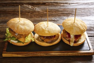 Burger in a row on a slate board and wood table