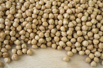Lot of whole fresh tan chickpea on wooden cutting board. Legumes