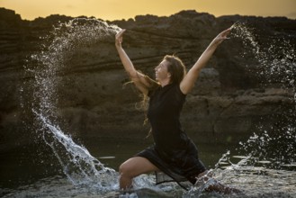 Middle-aged woman dancing and throwing water in the air, Maioris beach, llucmajor, Majorca,