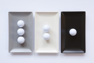 Different ceramic dishes with golf balls on over white background, rectangle dish