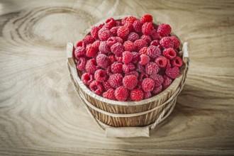 Bucket with raspberries on wooden board