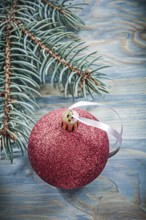 Pine branch red bauble on wooden board holidays concept