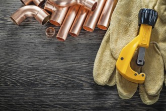 Plumbing brassware pipe cutter protective gloves on wooden board