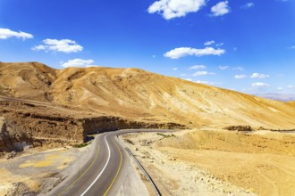 Desert on the shores of the Dead Sea. Israel. Asphalt highway meanders among the hills. Dead Sea