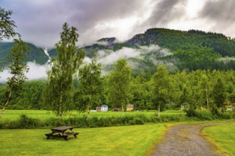 Rain-wet dirt road crosses a valley. Jostedalsbreen Park. Heavy clouds covered the sky. Valley