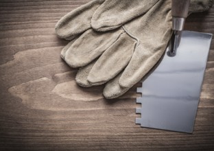 Working gloves and putty spattle on wood board