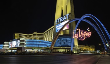 A picture of the STRAT Hotel, Casino and SkyPod and Las Vegas Boulevard Gateway Arches at night