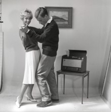 Learning to dance in the 1950s. A young copule is dancing in a photographers studio. The young