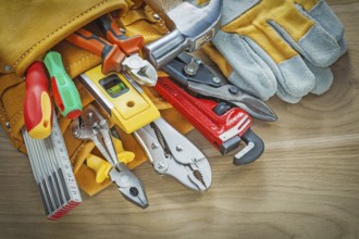 Tools in leather building belt on wooden board top view