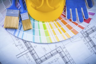 Building helmet protective glove paint brushes and color sampler on blueprint construction concept