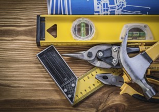 Blue blueprints construction level try square claw hammer pliers tin snips on wooden board