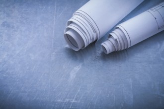 Rolled blueprints on metallic background construction concept