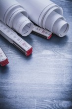 Vertical view rolled blueprints on wooden meter close up