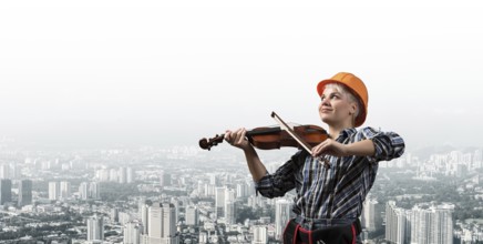 Beautiful young woman in safety helmet playing violin. Smiling professional female builder in