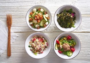 Four salad mix bowls healthy food on white wood table