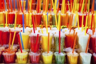 Colorful natural fresh fruits juice glasses with straw stacked in rows