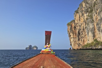 The Thai excursion boat floats to ocean island. The boat nose is decorated by multi-colored and