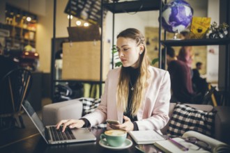 Business woman freelance working on computer notebook laptop and mobile phone, with coffee cup on