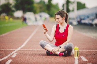 Beautiful fitneß girl uses smartphone at stadium after workout. Sports and healthy. Sport woman use