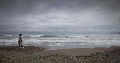 One woman walking on the coast beach. Stormy sky windy waves. Paphos Cyprus