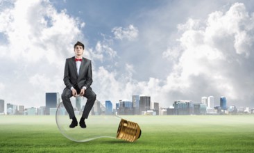 A businessman with glasses sits on a light bulb. concept of creativity in business
