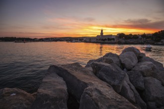 Town on a coast, with a stone fortification a harbour with a view of the sunset. Landscape photo of