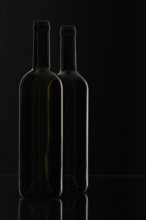 Two different bottles of wine on the black background