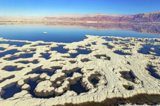 Dead Sea. Evaporated salt forms bizarre patterns on the water. Sunny winter day. The blue water is