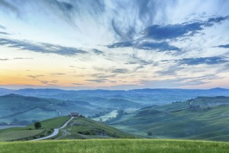 Italian valley in the dawn light with a farm on a hill