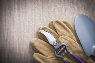 Sharp pruning shears hand spade and leather safety gloves on wood board agriculture concept