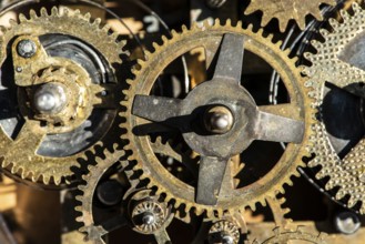 Close up metal gears mechanism. Golden colours. Hard light. Clock interior mechanism parts