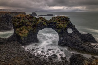 Rocky shore with a surf with foam on the water at Gatklettur