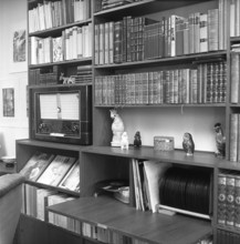 In the 1950s. Interior of a room and a wall with a bookshelf. Besides books it has room for a radio
