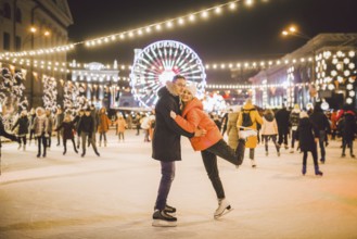 Beautiful Couple Ice Skating In City Centre. Young couple skating at a public ice skating rink