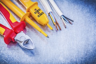 Yellow electrical tester wires wire cutter on metallic background electricity concept