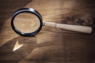 Vintage magnifer glass on old wooden board