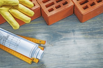 Red bricks leather working gloves construction plans wooden meter on wood board bricklaying concept