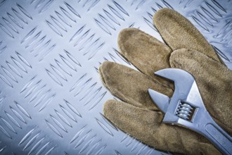 Safety gloves adjustable wrench on grooved metal plate construction concept