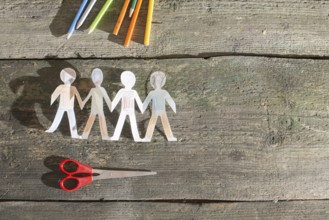 Paper made people figures. Painted white figures on wooden board