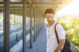 Handsome fit man in white shirt outdoor in city setting, looking away